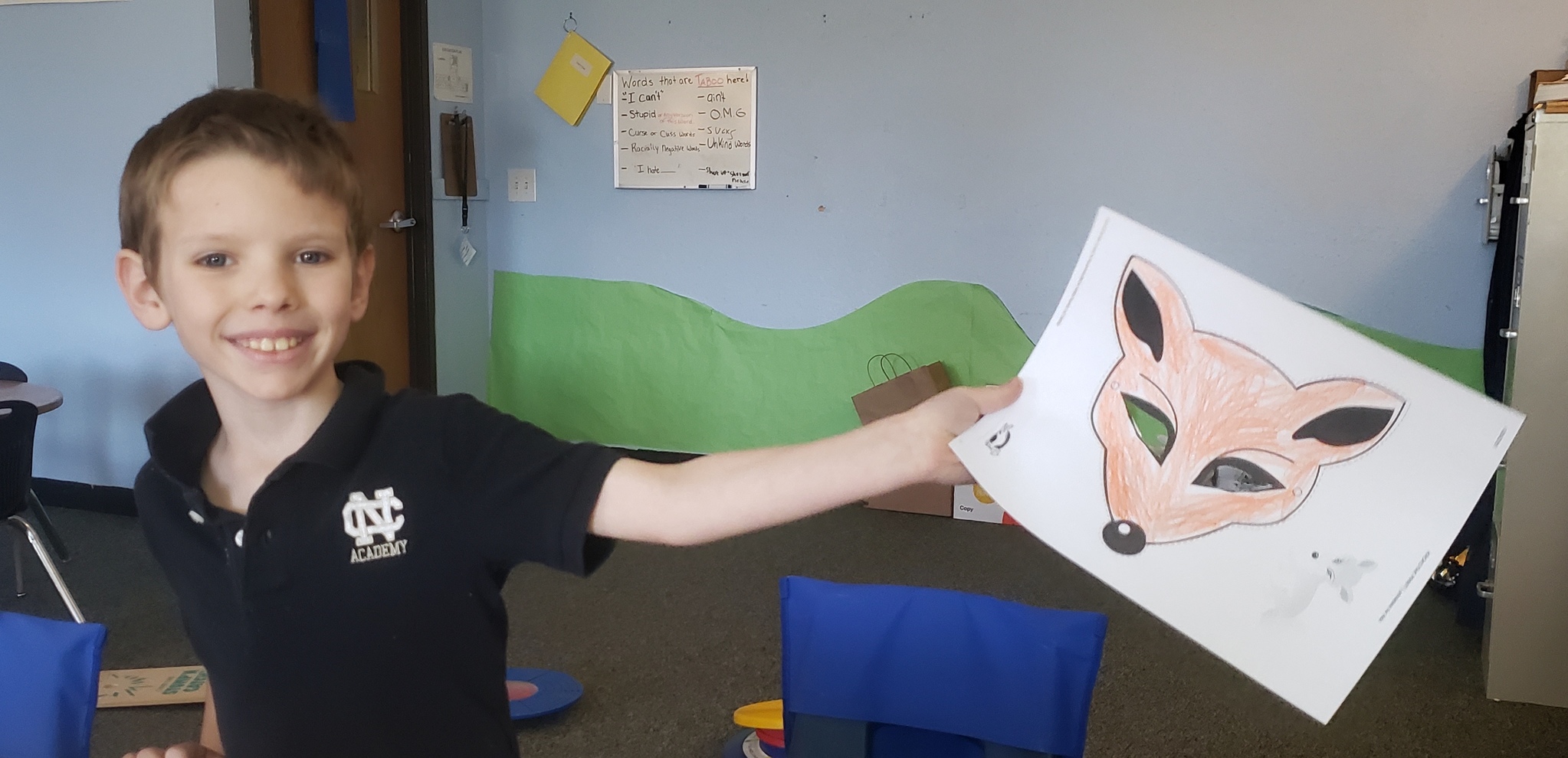 Student showing off his fox mask that he colored
